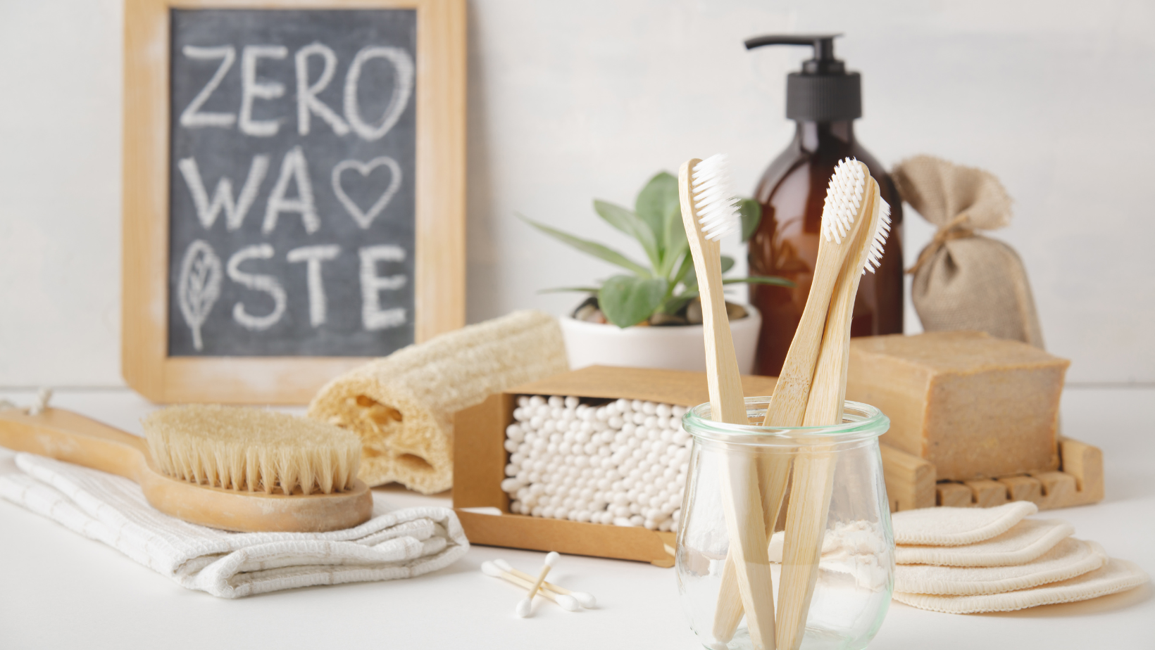 Zero waste written on blackboard with bamboo hair brush, toothbrush, cotton buds and other bathroom products